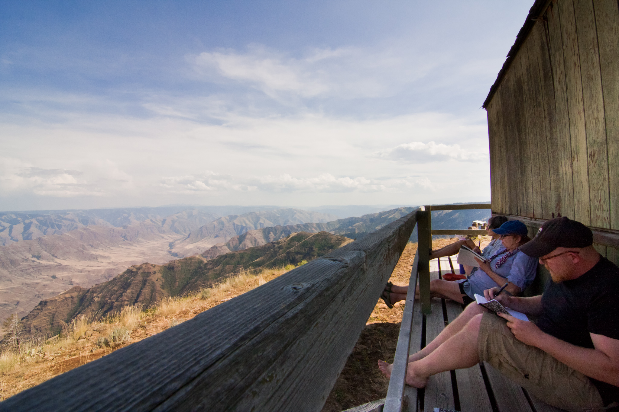 In love with the view and writing in journals, three writers sit on the deck of a fire outlook overlooking Hells Canyon in NE Oregon.